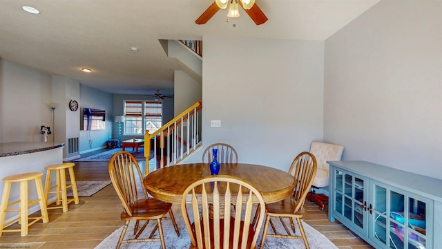 dining room featuring wood finish floors, stairway, visible vents, and a ceiling fan