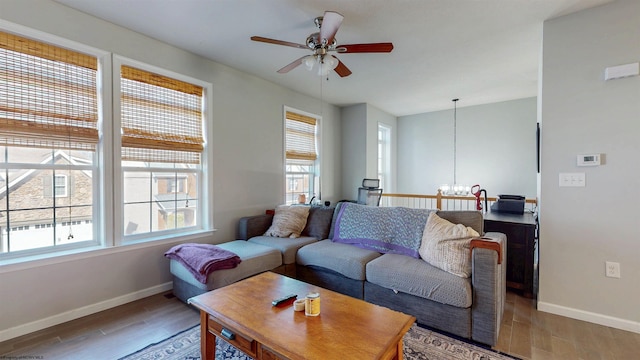 living room with ceiling fan with notable chandelier, light wood-type flooring, and baseboards