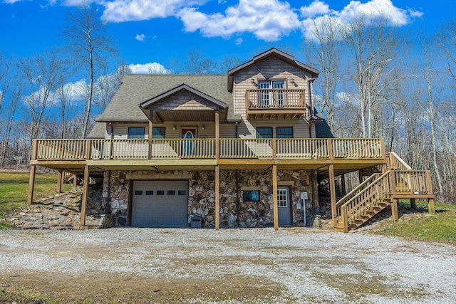 view of front of home featuring dirt driveway, a wooden deck, roof with shingles, stone siding, and an attached garage