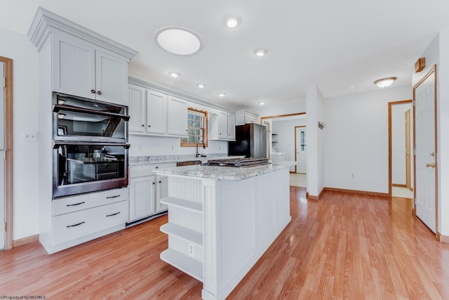 kitchen with a center island, black appliances, light wood-style floors, and open shelves