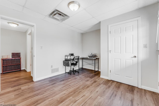 office space with visible vents, a paneled ceiling, and wood finished floors