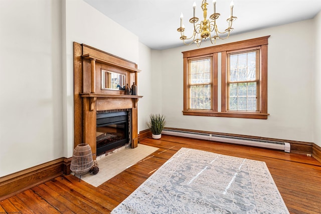 living area featuring a baseboard heating unit, a fireplace with flush hearth, an inviting chandelier, and wood-type flooring