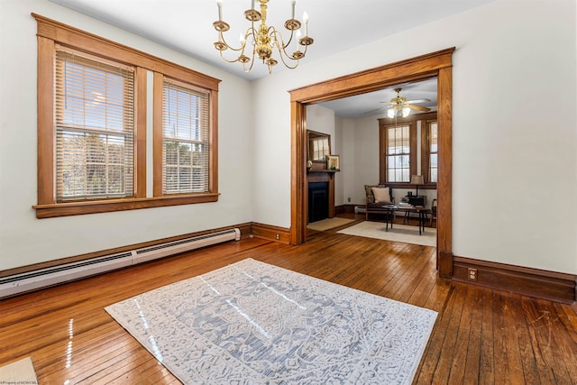 interior space with a fireplace with flush hearth, a notable chandelier, wood-type flooring, baseboards, and baseboard heating