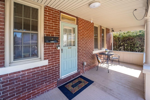 property entrance featuring brick siding and covered porch