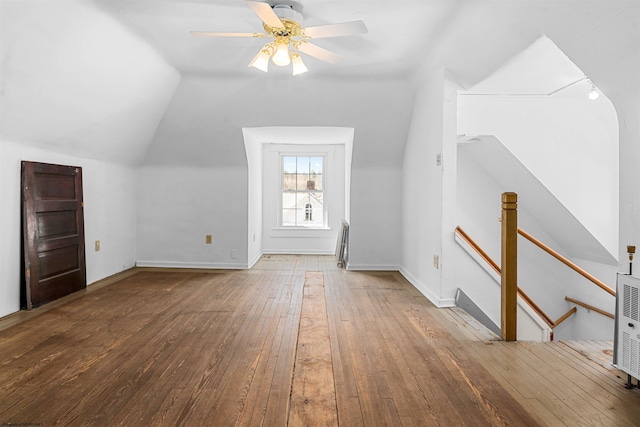 additional living space featuring radiator, a ceiling fan, baseboards, vaulted ceiling, and wood-type flooring