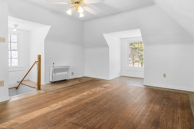 additional living space featuring heating unit, a healthy amount of sunlight, ceiling fan, and wood-type flooring