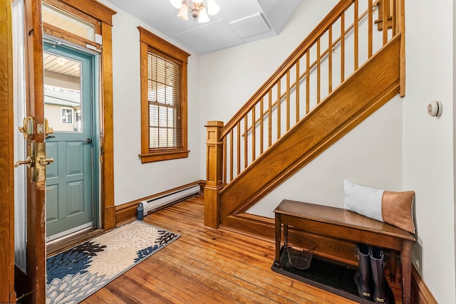 foyer entrance with baseboards, baseboard heating, hardwood / wood-style floors, and stairs