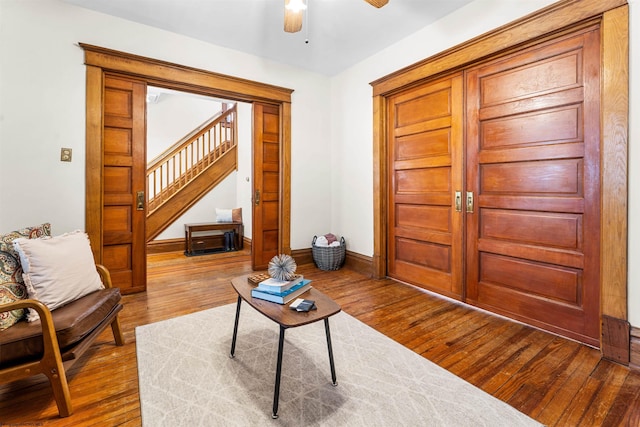 interior space featuring ceiling fan, baseboards, hardwood / wood-style floors, and stairs