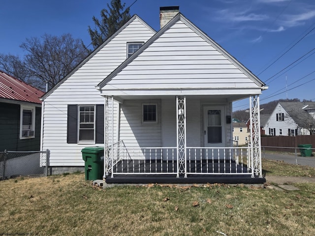 bungalow with a front lawn, a porch, a chimney, and fence