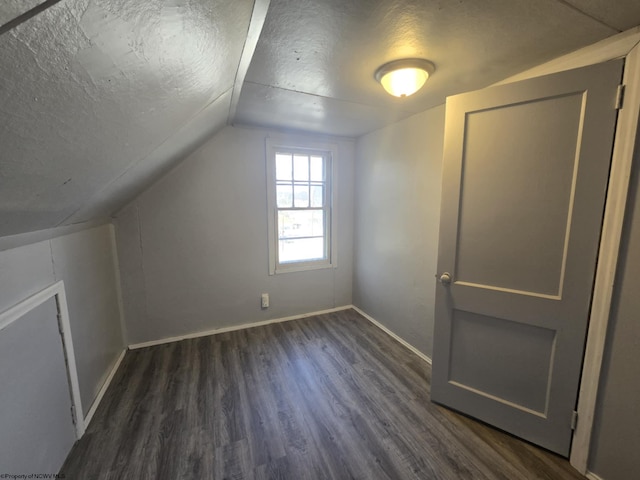 additional living space with lofted ceiling, baseboards, dark wood-style flooring, and a textured ceiling