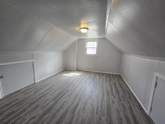 bonus room with vaulted ceiling, a textured ceiling, baseboards, and wood finished floors