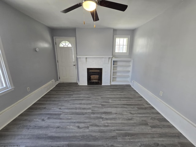 unfurnished living room featuring a fireplace, a ceiling fan, dark wood-type flooring, and baseboards