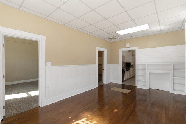 unfurnished living room featuring a drop ceiling, visible vents, wainscoting, and wood finished floors