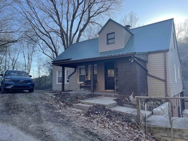 view of front of property featuring metal roof, covered porch, and a chimney