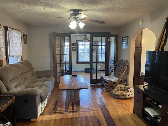 living area featuring arched walkways, a textured ceiling, ceiling fan, and hardwood / wood-style floors