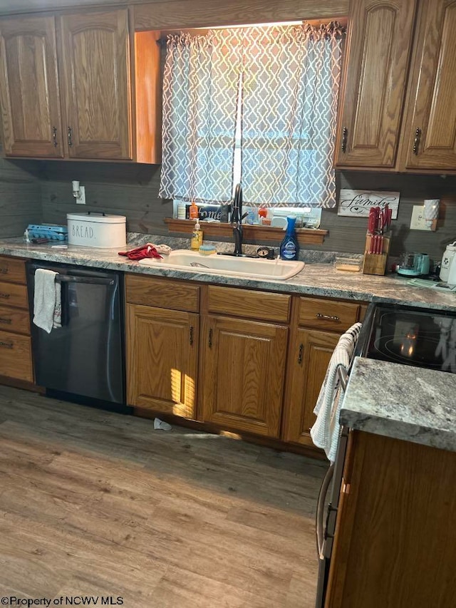 kitchen featuring a sink, dishwasher, light wood-style flooring, and brown cabinetry