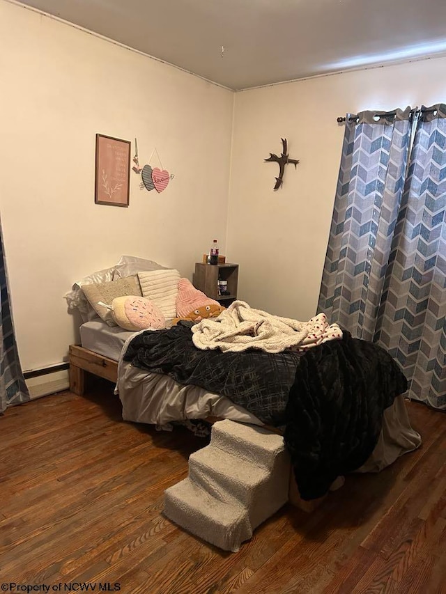 bedroom featuring a baseboard heating unit and wood finished floors