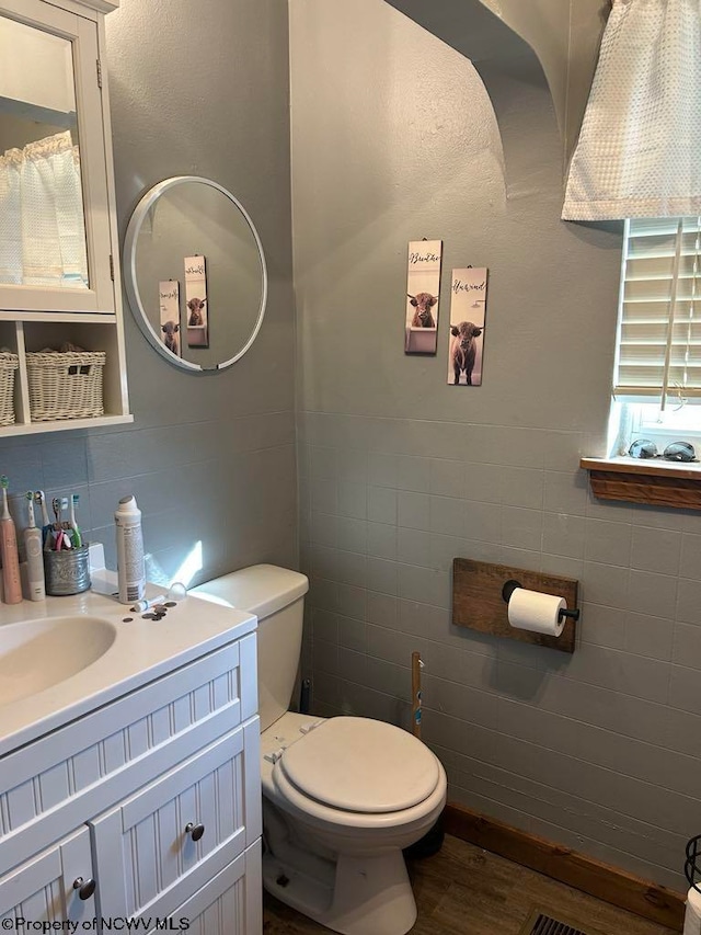 bathroom with vanity, toilet, tile walls, and wood finished floors