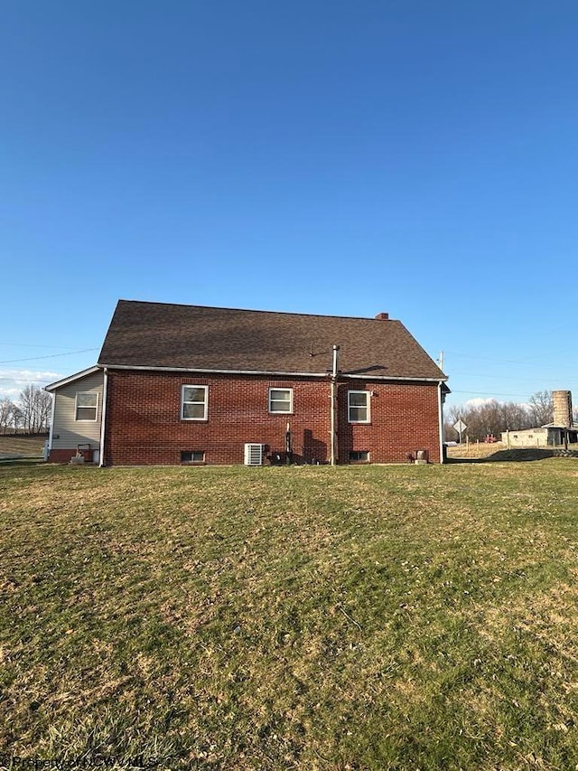 view of home's exterior featuring a yard, brick siding, and central AC unit