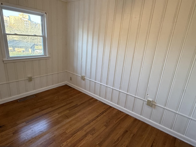 unfurnished room featuring visible vents, baseboards, and dark wood-style flooring