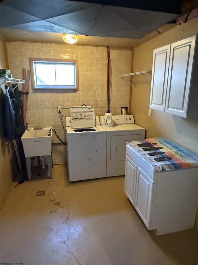 washroom with cabinet space, washer and dryer, and a sink