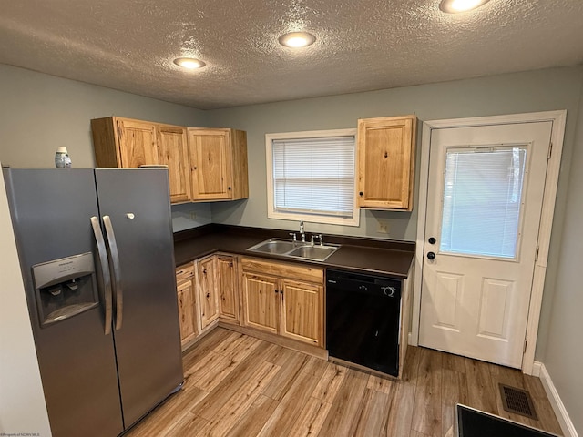 kitchen featuring visible vents, a sink, dark countertops, stainless steel fridge with ice dispenser, and dishwasher