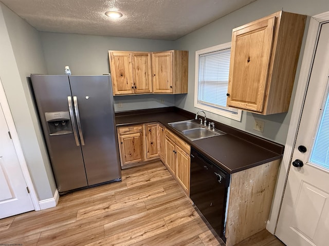 kitchen featuring dark countertops, black dishwasher, stainless steel refrigerator with ice dispenser, and a sink