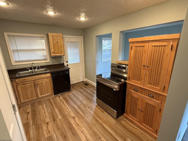 kitchen with stainless steel electric range oven, a sink, light wood-style floors, dishwasher, and dark countertops