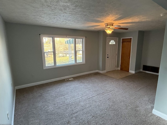 interior space with baseboards, a ceiling fan, visible vents, and a textured ceiling