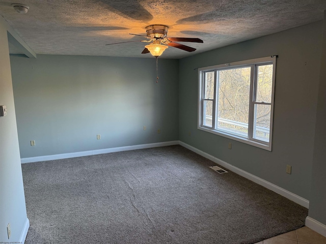 empty room with visible vents, baseboards, carpet, ceiling fan, and a textured ceiling