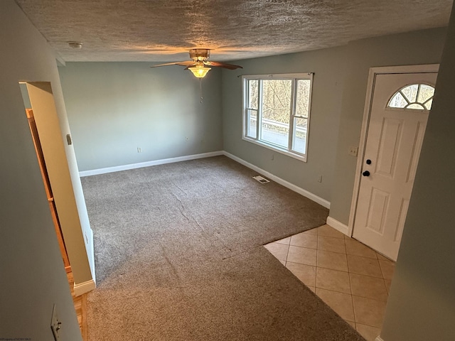 entrance foyer with a textured ceiling, light tile patterned floors, a ceiling fan, and light carpet