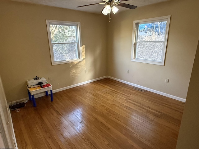 spare room featuring visible vents, baseboards, ceiling fan, and hardwood / wood-style flooring