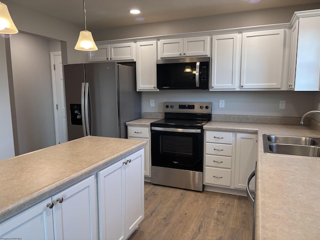 kitchen with light wood finished floors, a sink, white cabinetry, stainless steel appliances, and light countertops