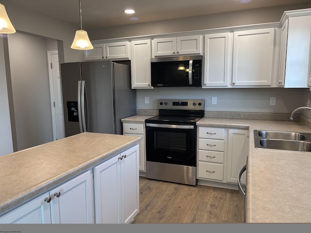 kitchen featuring light countertops, light wood-style flooring, white cabinets, stainless steel appliances, and a sink