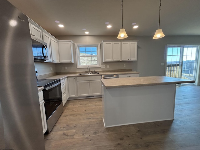 kitchen featuring light countertops, light wood-type flooring, appliances with stainless steel finishes, and a sink