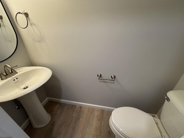 bathroom with toilet, baseboards, and wood finished floors