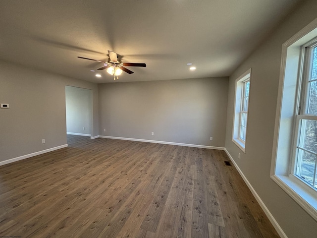 spare room with dark wood finished floors, a healthy amount of sunlight, baseboards, and a ceiling fan