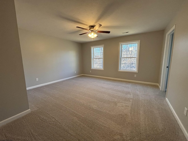 carpeted spare room featuring a ceiling fan, visible vents, and baseboards