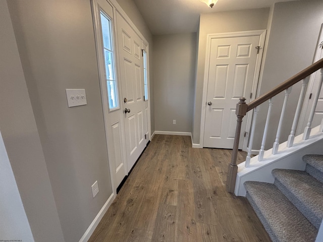 foyer with stairway, wood finished floors, and baseboards