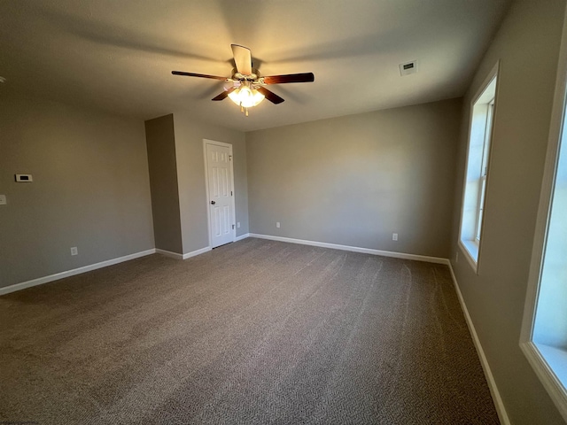 empty room with visible vents, baseboards, ceiling fan, and dark carpet