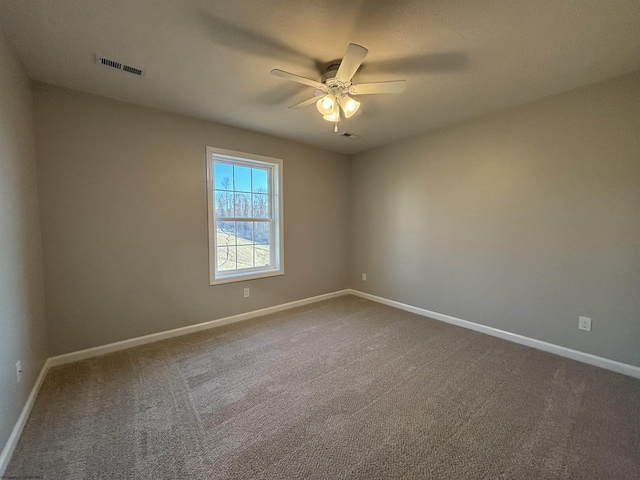 empty room with dark colored carpet, visible vents, baseboards, and ceiling fan