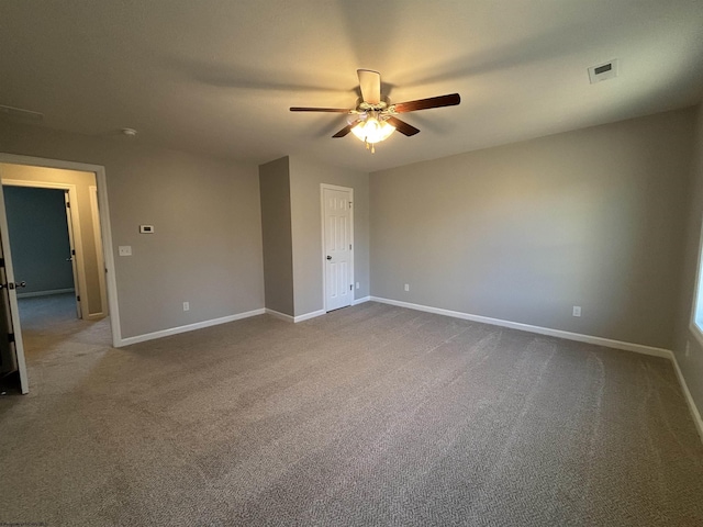 empty room with dark colored carpet, visible vents, baseboards, and a ceiling fan