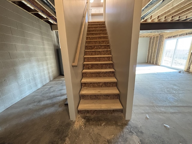 stairway featuring concrete floors and concrete block wall