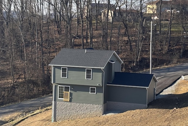 view of side of home with a shingled roof