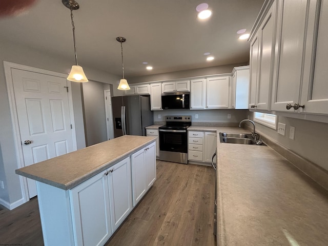 kitchen with a kitchen island, dark wood finished floors, a sink, stainless steel appliances, and white cabinetry