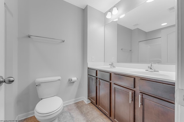 bathroom with a sink, toilet, double vanity, and tile patterned flooring