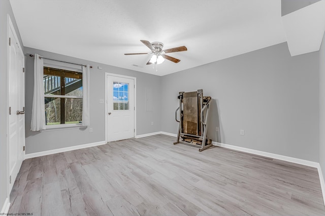 spare room with light wood-style flooring, a ceiling fan, and baseboards