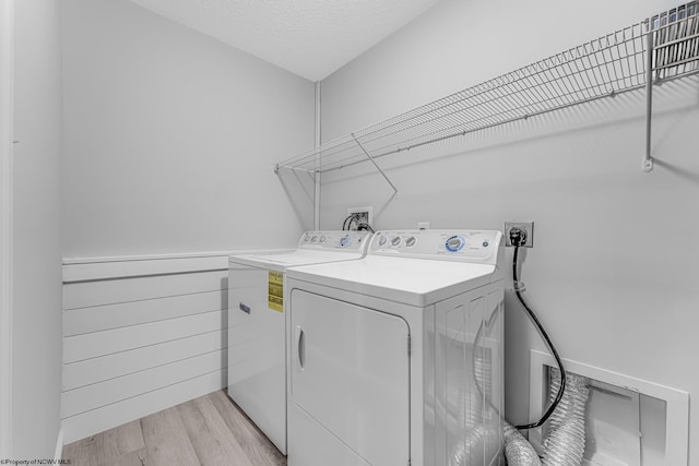 laundry area featuring washer and dryer, light wood-type flooring, a textured ceiling, and laundry area