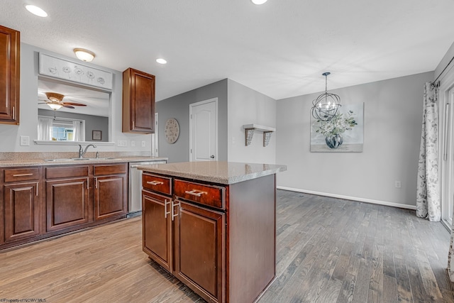 kitchen featuring a center island, stainless steel dishwasher, light wood-style floors, and a sink