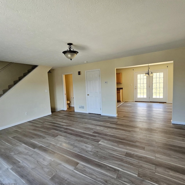 unfurnished living room with dark wood finished floors, stairway, a textured ceiling, and baseboards